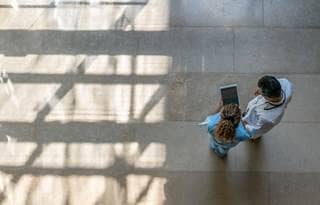 Two medical professionals review information on a tablet.