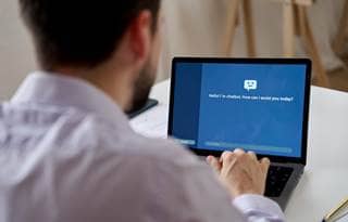 Business professional talking to an AI chatbot on their laptop.