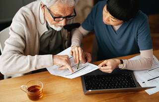 Medical professional and senior citizen reviewing insurance information.