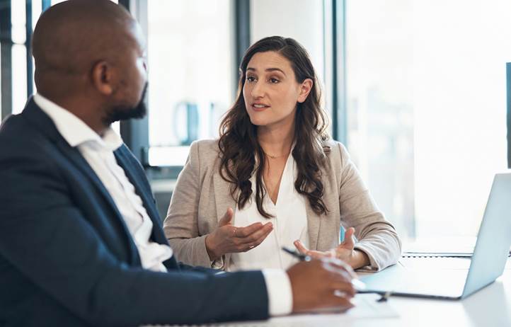 Two business professionals talking at a desk together