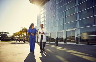 Doctor and nurse walking outside of a hospital.