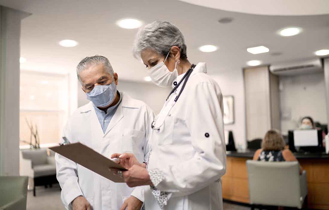Two doctors with masks on checking their charts.