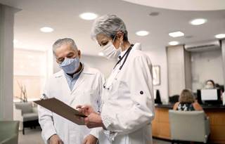 Two doctors with masks on checking their charts.