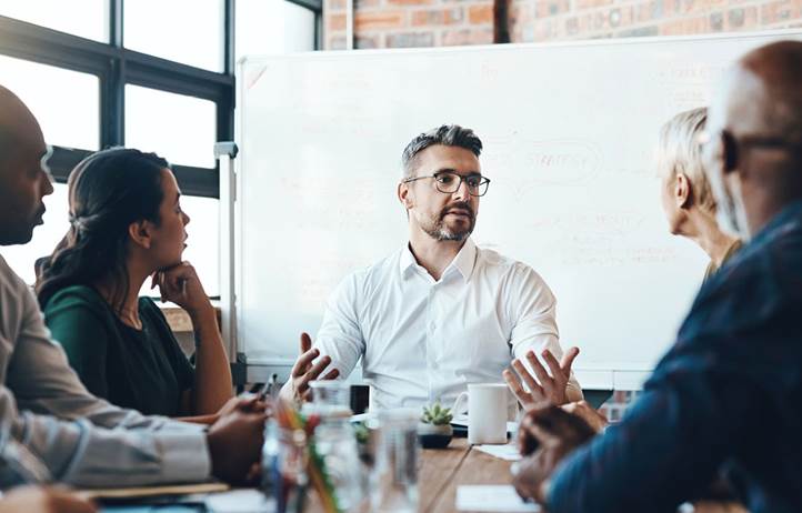 Business professionals sitting at a table discussing turning experience into sustainable performance