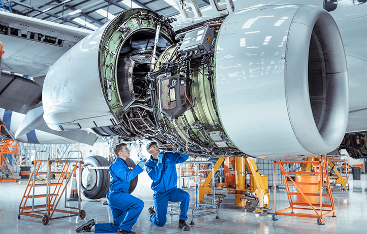 Two technicians working on the engine of an airplane.