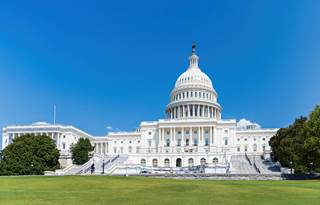 U.S. Capitol building against a bright blue sky.