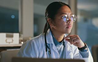 Medical professional looks at a computer.