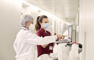 Healthcare professionals looking at their patient's charts in a hospital hallway.