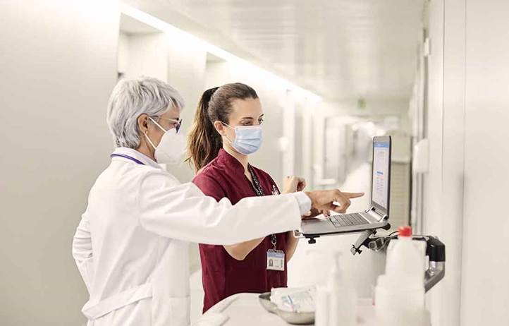 Healthcare professionals looking at their patient's charts in a hospital hallway.