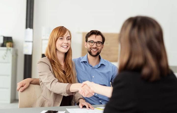 Couple shaking hands with their financial advisor.