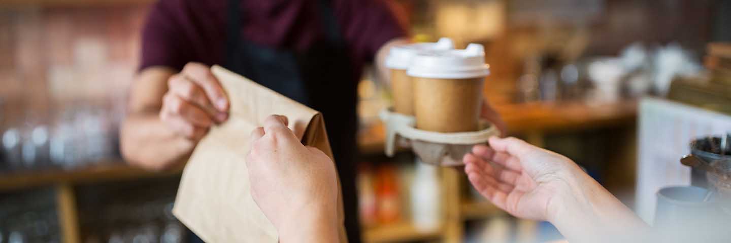 Barista handing a customer their coffee and pastry.