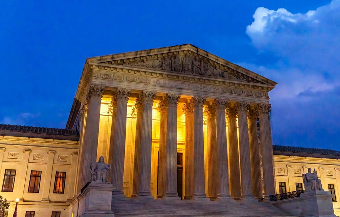 Supreme Court building of the United States featured at night time