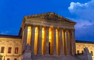 Supreme Court building of the United States featured at night time