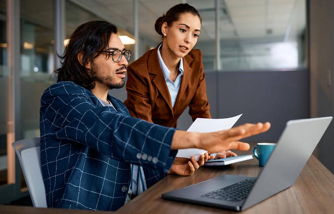 Two technology consultants reviewing data on their laptop.