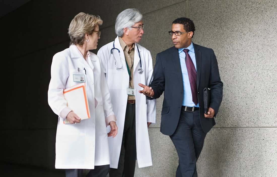 Business professional walking alongside two doctors.
