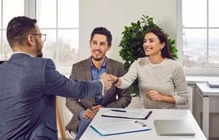 Wealthy couple shaking hands and talking to their financial advisor.