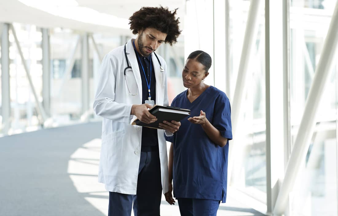 Doctors reviewing their medical charts in a hospital hallway.