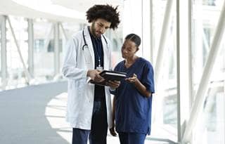 Doctors reviewing their medical charts in a hospital hallway.