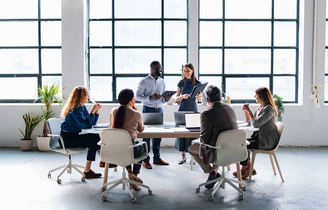 Group of business professionals discussing post-acquisition reporting in a modern office.