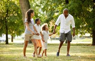 Family holding hands and walking in a park.