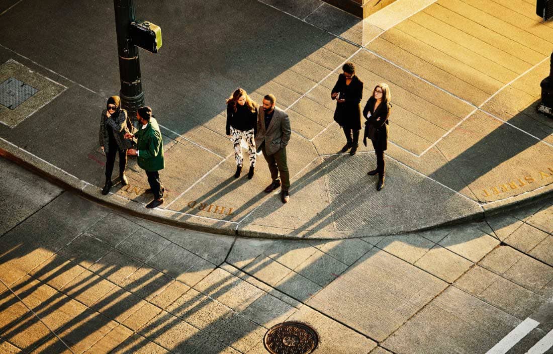 Aerial overview of businesspeople waiting to cross a busy city street.