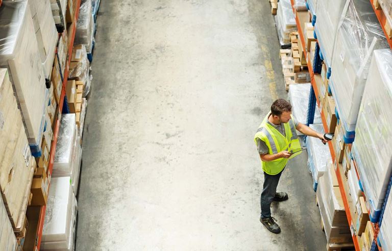 Warehouse worker checkng shelving units.