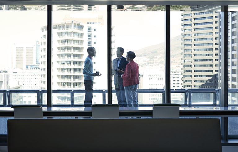 Three people talking by window