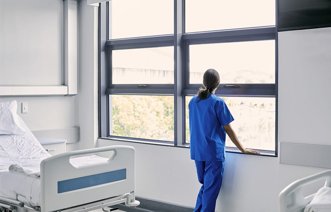 A nurse standing against a window