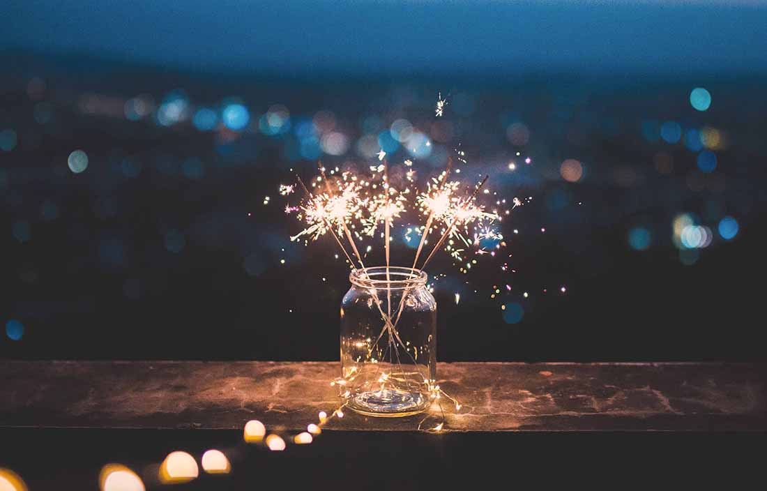 Close up photo of sparkler fireworks going off inside of a glass jar.