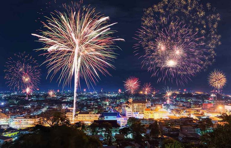 Fireworks exploding over a downtown city area.