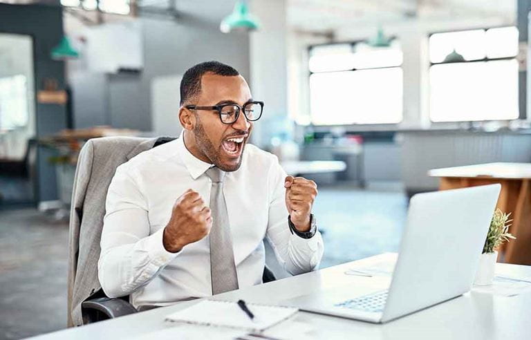 Business professional celebrating in front of their laptop while sitting.