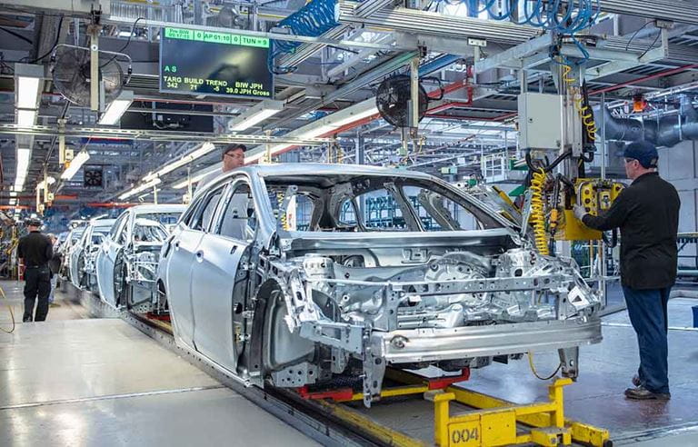 Factory workers assembling a car.