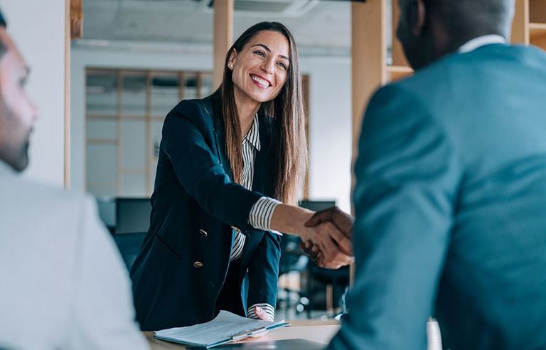 Business professionals smiling and shaking hands.