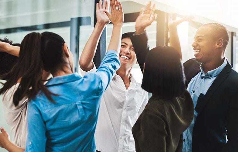 Business professionals high-fiving each other in celebration.