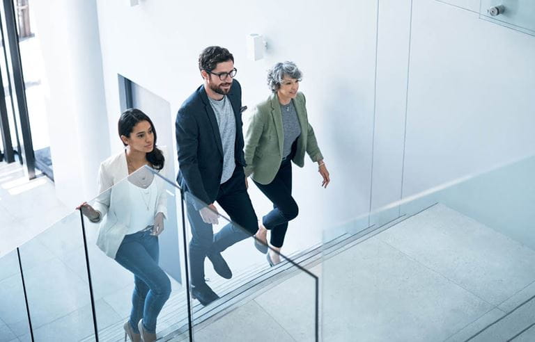 Business professionals walking up the stairs in a modern, clean office space.