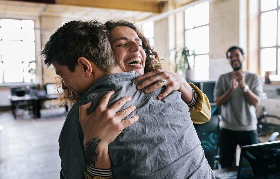 Two business professionals celebrating by hugging one another