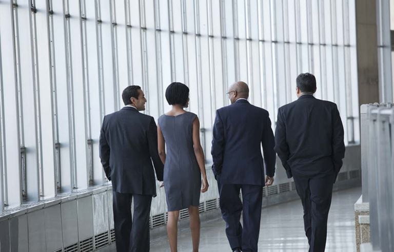 Group of business professionals walking in a hallway.