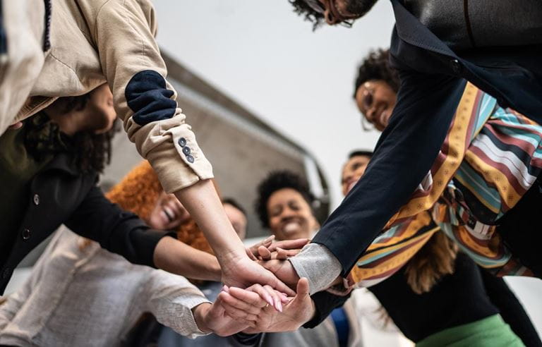 Group of cybersecurity professionals putting their hands together in celebration.