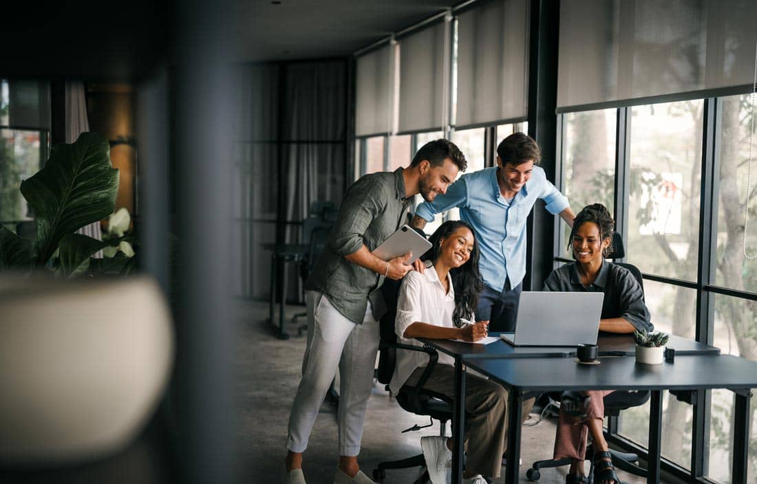 Group of coworkers gathered around a laptop.