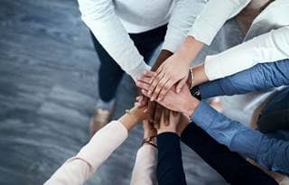 Group of coworkers putting their hands together.