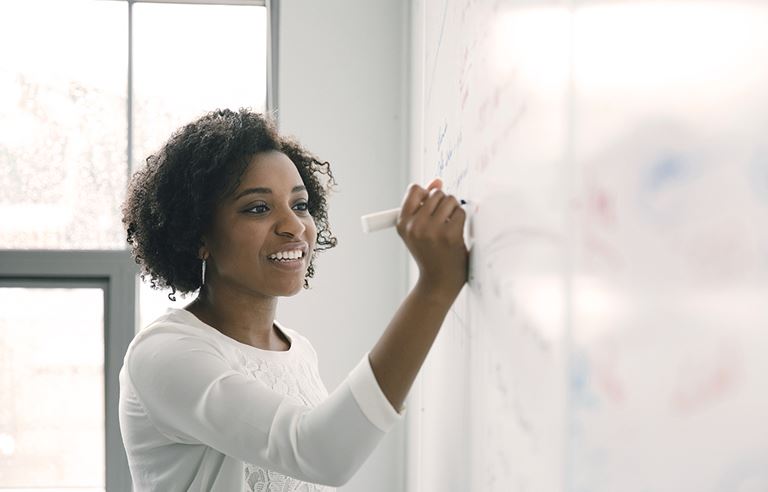 Business woman writing strategies and brainstorming on a whiteboard.