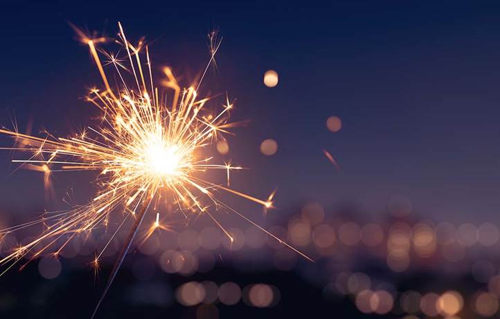 Sparkler in front of blurry image of commercial buildings