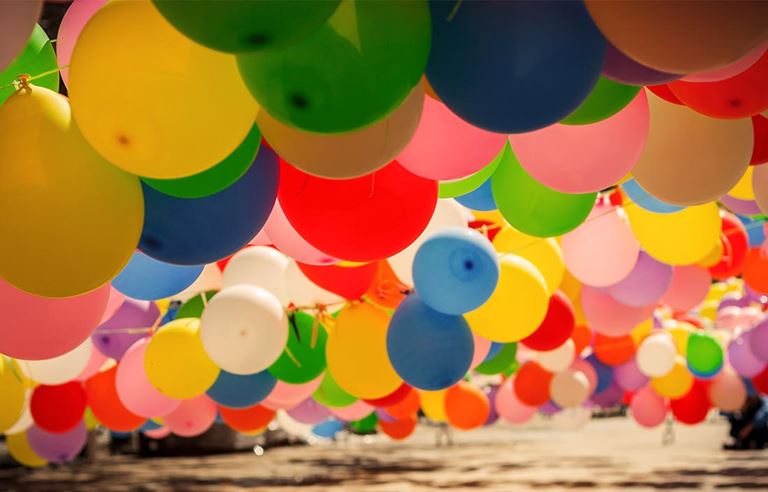 Colored balloons hung in lines from strings over what appears to be water