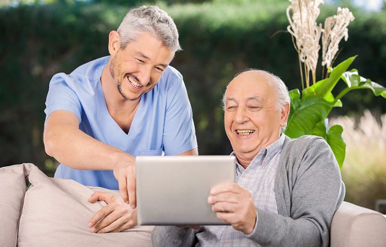 Image of caretaker and older man using a tablet device