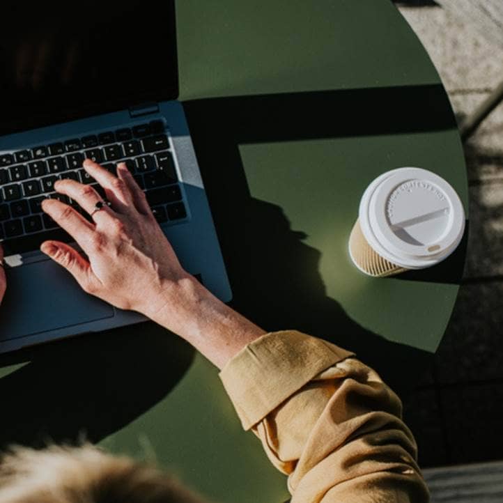 Person working on their laptop while drinking coffee.