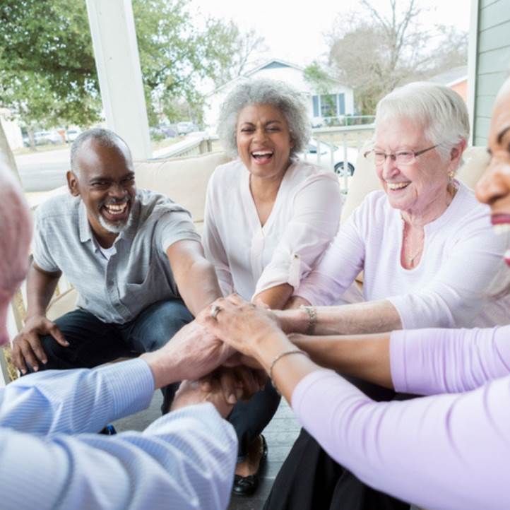 Group of senior citizens putting their hands together.