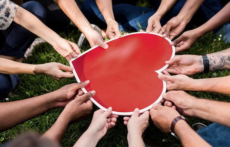 Many hands holding a paper heart