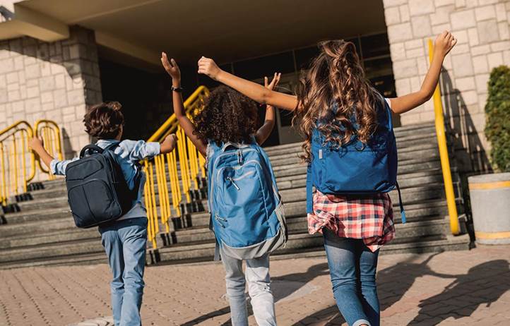 Three young students running into school building