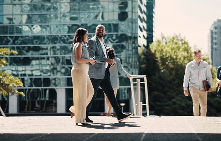 Two businesspeople walking between office buildings on a sunny day