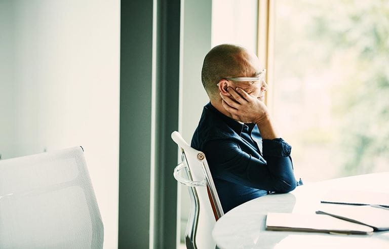 Portrait of smiling businessman resting chin on hand in office conference room during meeting about ESG real estate investments